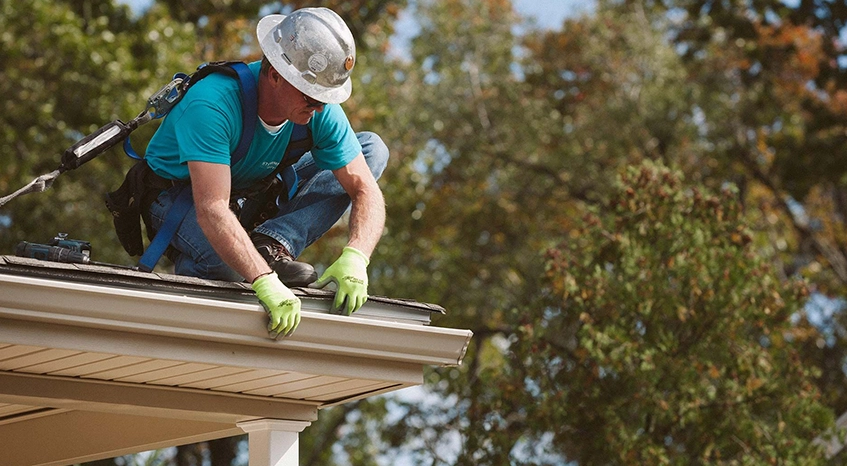 Worker Performing Gutter Cleaning on Residential Roof
