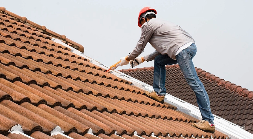 Worker Performing Roof Rejuvenation On Tiled Residential Roof